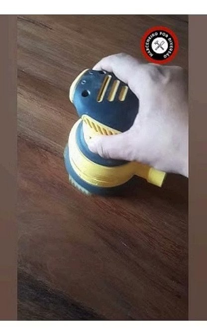Orbital sander preparing hardwood surface with progressive grit sandpaper