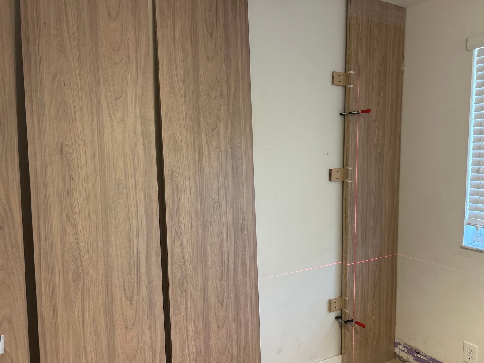 Wood slat paneling being fitted and clamped during installation by the M11 Design Group team
