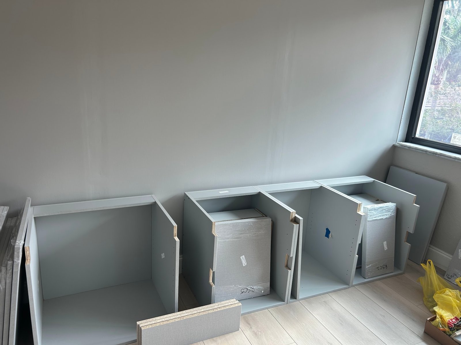 Labeled cabinet components laid out in order in the room before assembly by M11 Design Group