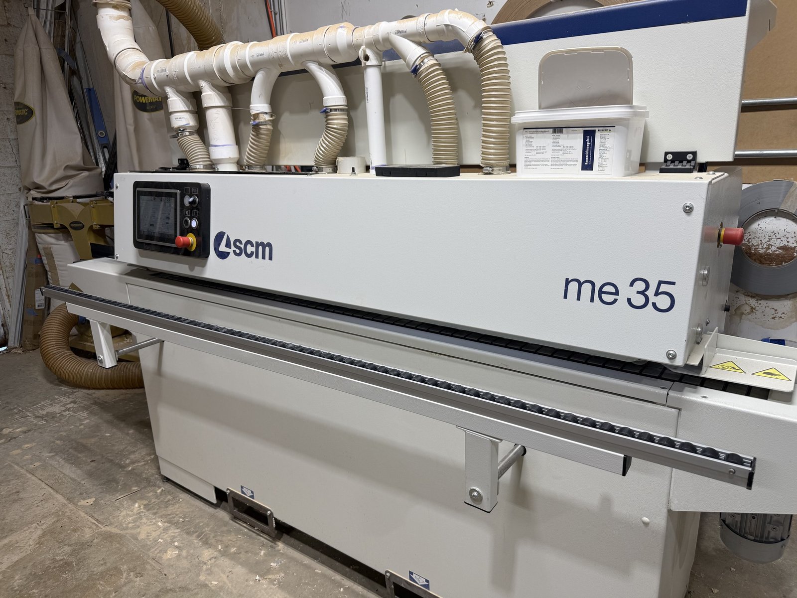 Edgebander applying edge tape to cabinet components in the M11 Design Group shop