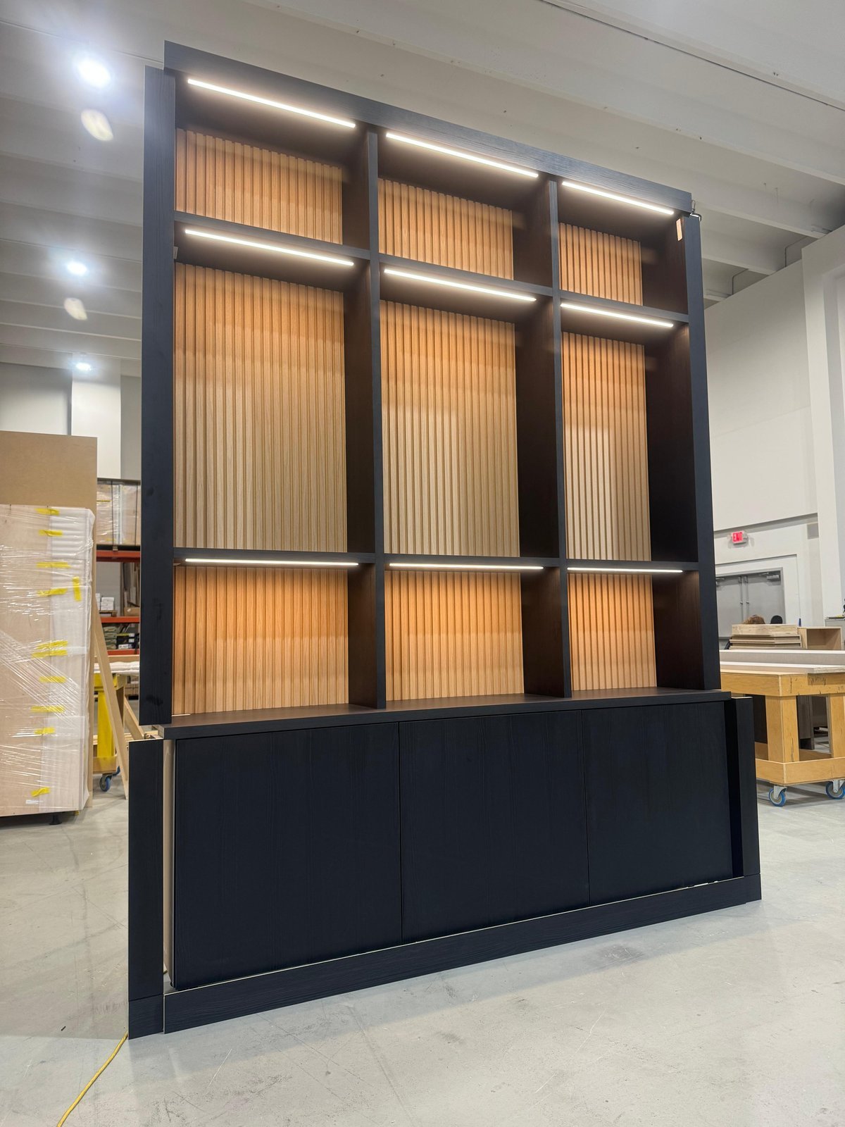 Black bookcase with oak slat back and LED lighting pre-assembled in the M11 Design Group shop before installation day