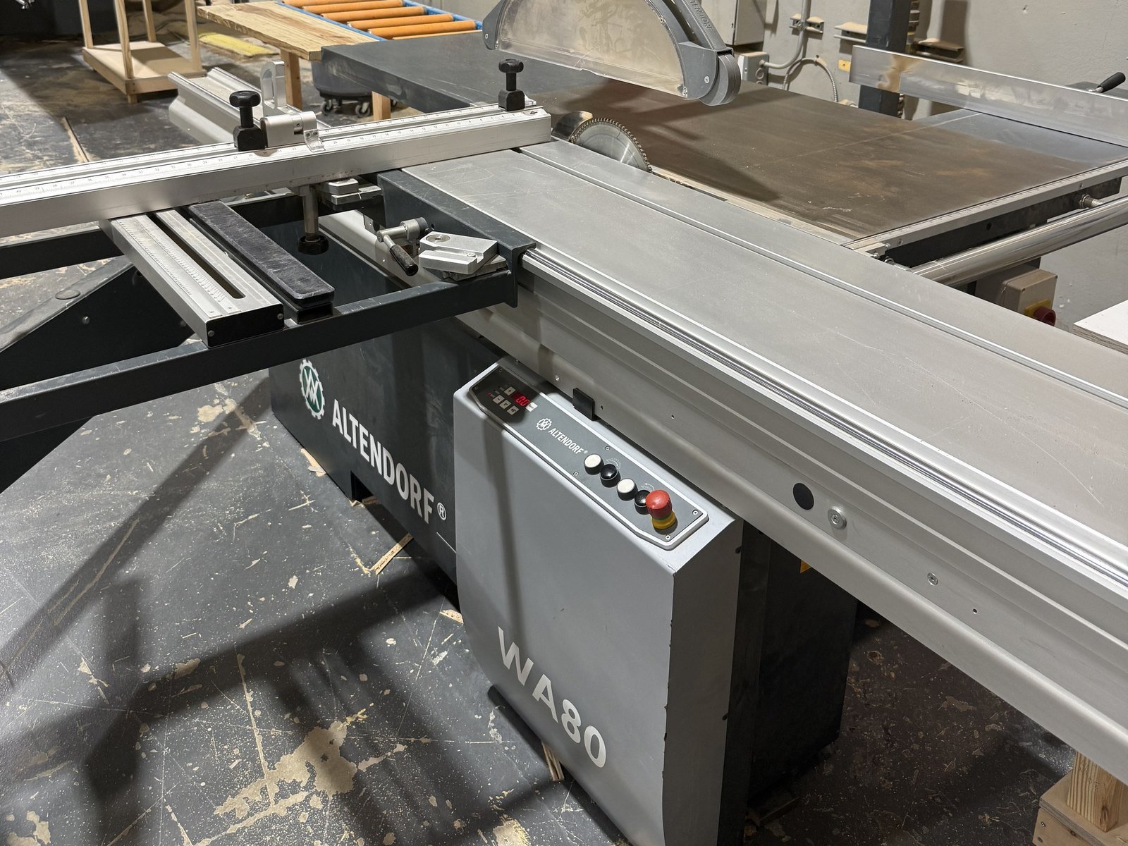 Sliding table panel saw on the M11 Design Group production floor, where cabinet panels are cut to size